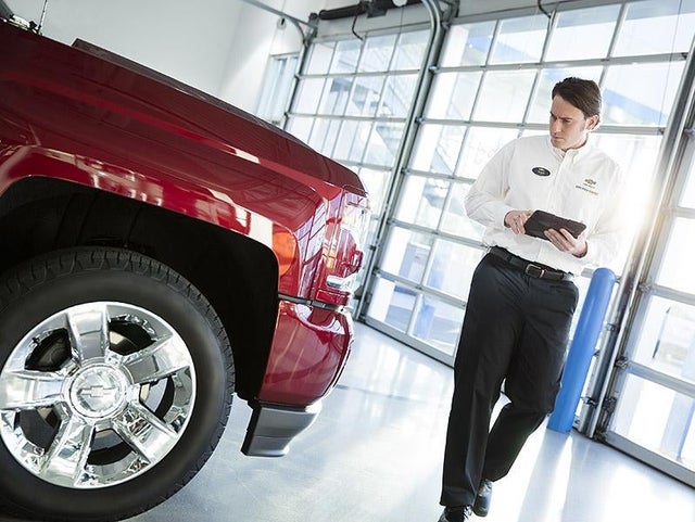 Service center employee inspects vehicle while holding tablet.
