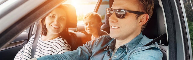 Family taking a road trip with the sun shining through the vehicle.